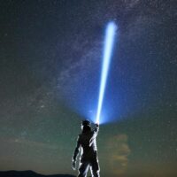 cosmonaut-shining-flashlight-into-magnificent-night-sky